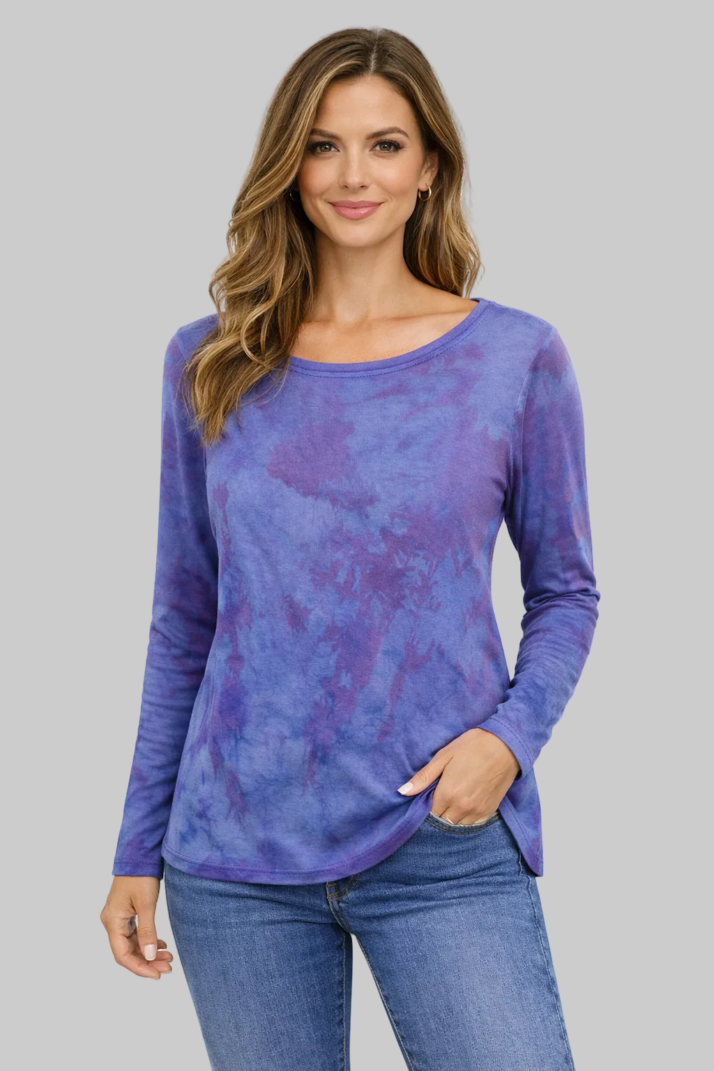 Woman wearing a purple tie-dye long-sleeve top and blue jeans on a white background